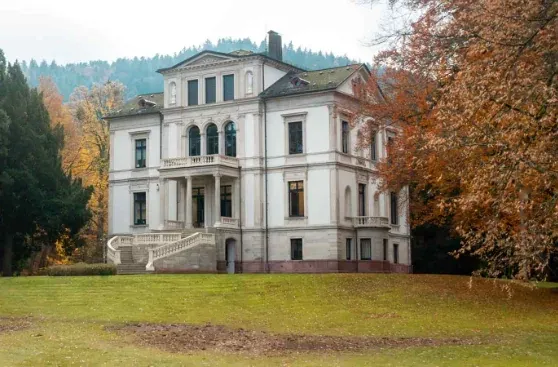 Grande demeure de caractère à façade blanche dans un parc arboré.