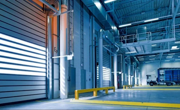 Intérieur d’un entrepôt logistique avec quais de chargement, portes sectionnelles et camion.