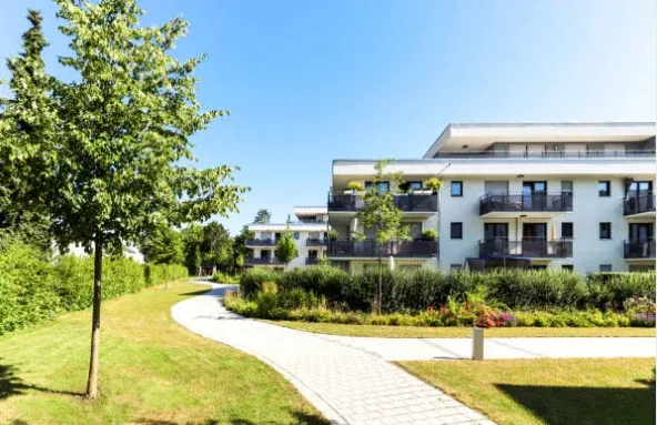 Résidence immobilière contemporaine entourée d’espaces verts et d’une allée piétonne.
